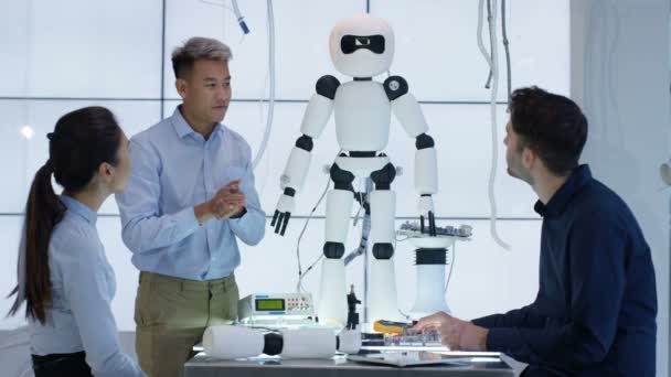 Équipe de conception technique 4K collaborant à la construction d'un robot dans un laboratoire moderne 