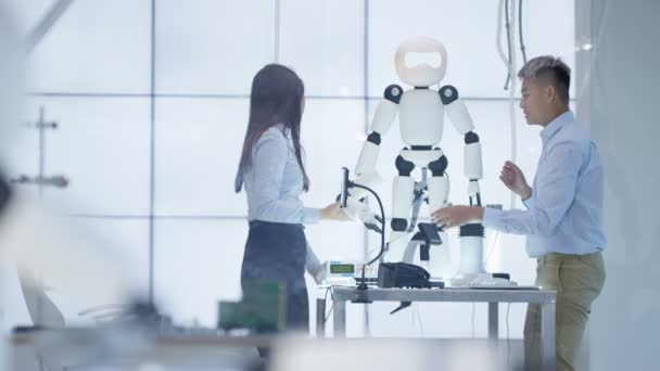 Ingénieurs techniques 4K travaillant sur la construction d'un robot automatisé dans un laboratoire moderne .