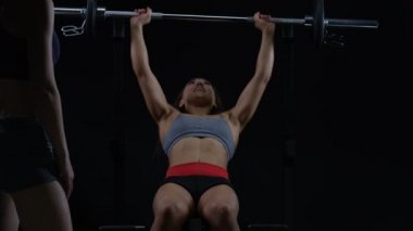 4k uygun genç kadının kişisel antrenör izlerken barbell bench press yapması