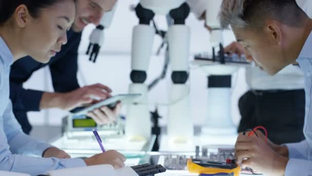 Équipe de conception technique 4K collaborant à la construction d'un robot dans un laboratoire moderne 