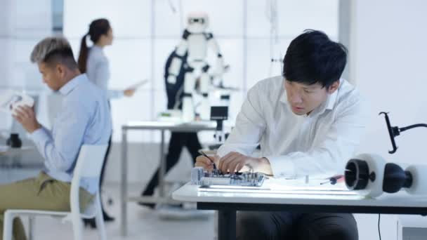 Équipe de conception technique 4K travaillant sur la construction d'un robot dans un laboratoire moderne 