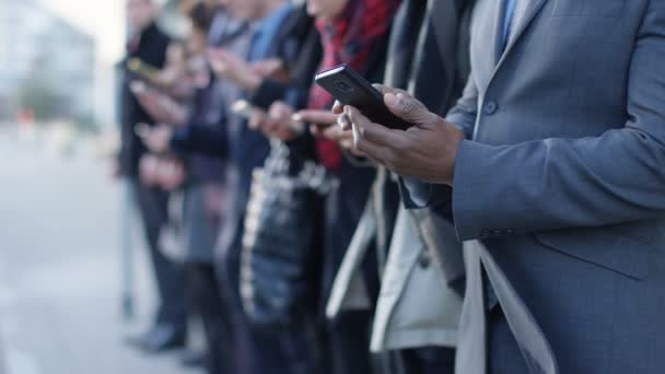Grupo Empresarial Diverse Mirando Los Teléfonos Inteligentes Mientras Espera Línea — Vídeo de stock