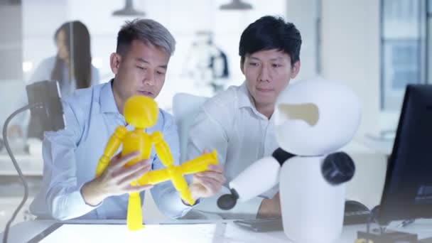 Ingénieurs en électronique asiatiques 4K travaillant en laboratoire avec un prototype de robot 