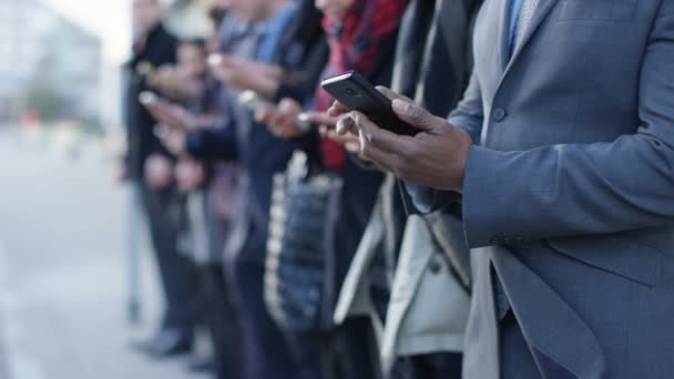 Grupo Empresarial Diverse Mirando Los Teléfonos Inteligentes Mientras Espera Línea — Vídeos de Stock