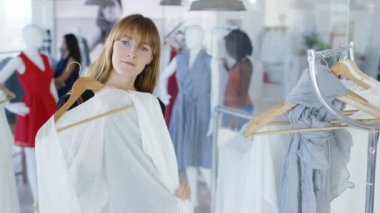 Moda Giyim Mağazası aynaya bakarak ve giysi kadar tutan kadın müşteri. Arka planda alışveriş diğer müşteriler ile Mirror's pov görüldü.