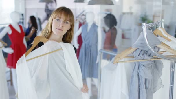 在时尚服装店里 女顾客举着服装 照镜子 从镜子的 Pov 看与其他顾客在背景购物 — 图库视频影像
