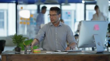 Arka planda çalışan meslektaşları ile modern ofis onun masasında cep telefonuyla konuşan işadamı.