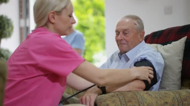 Junge Krankenschwester Überprüft Pflegeheim Den Blutdruck Eines Älteren Mannes — Stockvideo