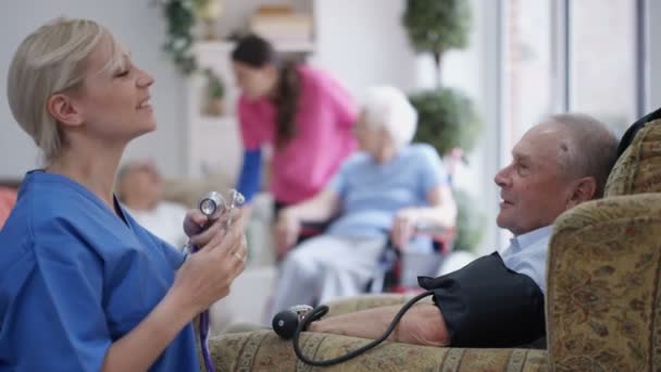 Young Nurse Checking Elderly Man Blood Pressure Nursing Home — Stock Video