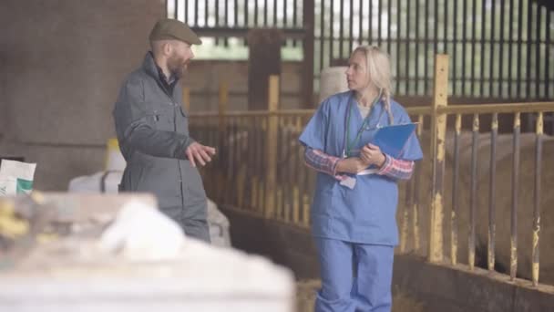 兽医在农场建筑内部与农民交谈 — 图库视频影像