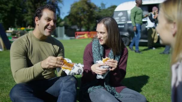 愉快的朋友聊天和吃快餐从汉堡面包车在社区活动 — 图库视频影像