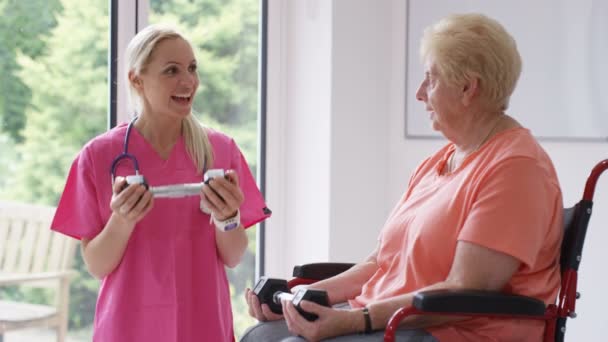 Krankenschwester Altenheim Zeigt Älteren Dame Rollstuhl Einige Übungen Mit Widerstandsbändern — Stockvideo