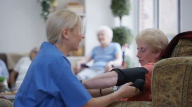 Kontrol yaşlı bayanın kan basıncı bakım evinde genç hemşire.