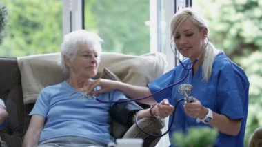 Bakım hemşire Huzurevi yaşlı bayanın kan basıncı kontrol.