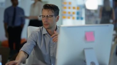 Arka planda çalışan meslektaşları ile modern ofis onun masasında cep telefonuyla konuşan işadamı.