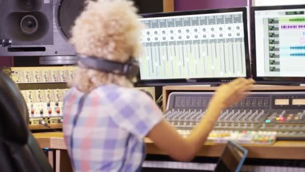 レコーディング スタジオのミキシング デスクでノート パソコンを使用しての の若いサウンド エンジニア — ストック動画