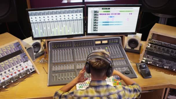 年轻音响工程师在录音室的混音台工作 — 图库视频影像