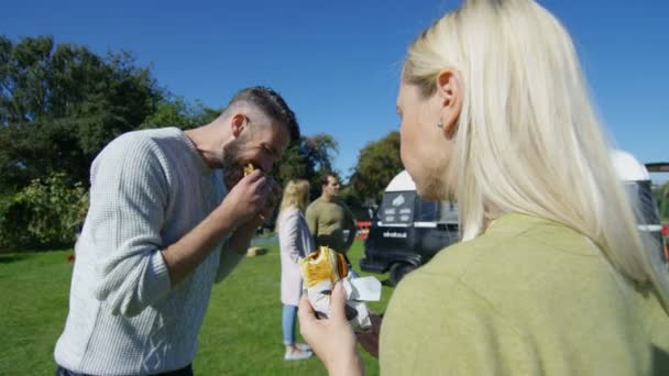 愉快的朋友聊天和吃快餐从汉堡面包车在社区活动 — 图库视频影像