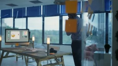 Tasarımcı geç saatlere kadar ofiste, bilgisayarda çalışarak ve telefon görüşmesi.