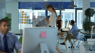 Arka planda bir toplantıda meslektaşları ile masada gülümseyen Tasarımcısı portresi