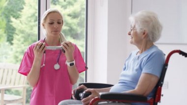 Yatılı bakım ev hemşire yaşlı Bayan tekerlekli sandalyede ağırlıklar ile bazı egzersizleri gösterilen.