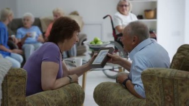 Neşeli kıdemli erkek ve kadın bir resmi bakarak ve bakım evinde sohbet.