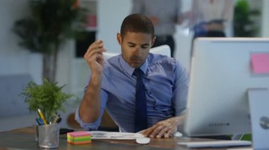 Arka planda çalışan meslektaşları ile modern ofisindeki bilgisayarda çalışan tasarımcı