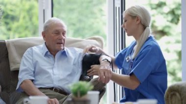 Kontrol yaşlı adamın kan basıncı bakım evinde genç hemşire.