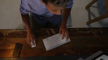 Aşağı, onun masasında bilgisayarda çalışan office tasarımcısında seyir yüksek açılı görünüş.