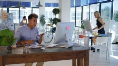 Arka planda çalışan meslektaşları ile modern ofis onun masasında cep telefonuyla konuşan işadamı.