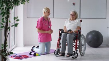 Yatılı bakım ev hemşire yaşlı Bayan tekerlekli sandalyede ağırlıklar ile bazı egzersizleri gösterilen.
