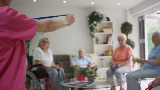 Молодая Медсестра Показывает Пожилым Людям Несколько Упражнений Браслетом Сопротивления Доме — стоковое видео