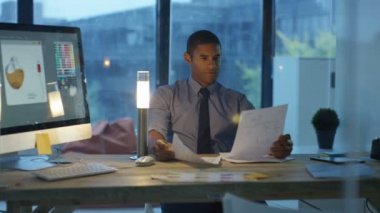 Tasarımcı geç saatlere kadar ofiste, bilgisayarda çalışarak ve telefon görüşmesi.