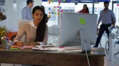 Arka planda çalışan meslektaşları ile yaratıcı ofis masasında çalışan Tasarımcısı.