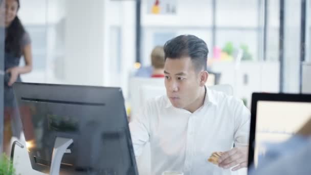 Asiatischer Geschäftsmann Frühstückt Auf Seinem Schreibtisch Und Spricht Mit Einer — Stockvideo