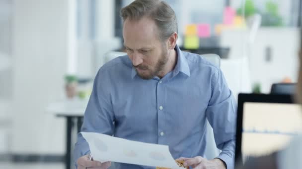 Affärsman Med Frukost Vid Sitt Skrivbord Och Tittar Pappersarbete — Stockvideo