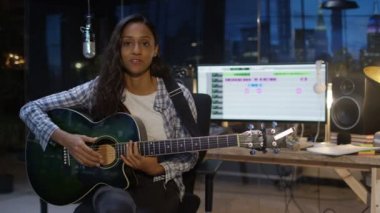 Yeni şarkı sunulması ve akustik gitar çalmak esmer kadın 