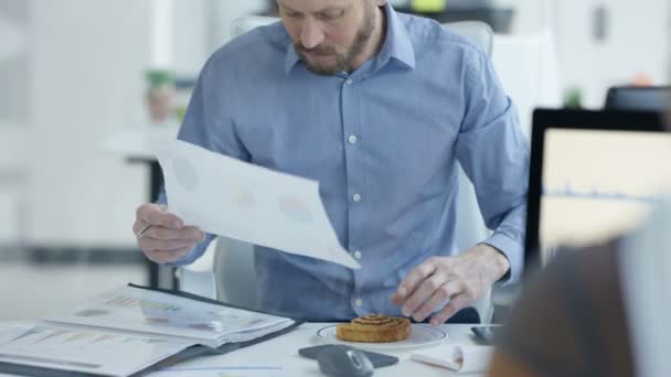 Zakenman Ontbijten Zijn Bureau Papierwerk Kijken — Stockvideo