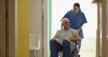 4 k bakım tıbbi çalışan yaşlı adam tekerlekli sandalye hastanede yoluyla bastırıyor 
