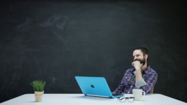 dizüstü bilgisayarda çalışan ve kara tahta ilham için bakarak 4 k Hipster adam