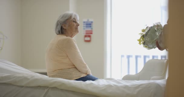 病室で シニア カップル男は病気の妻を訪問し 花を与える — ストック動画