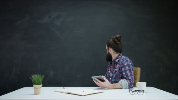 Hipster Man Werken Tablet Kijken Naar Schoolbord Achter Voor Inspiratie — Stockvideo