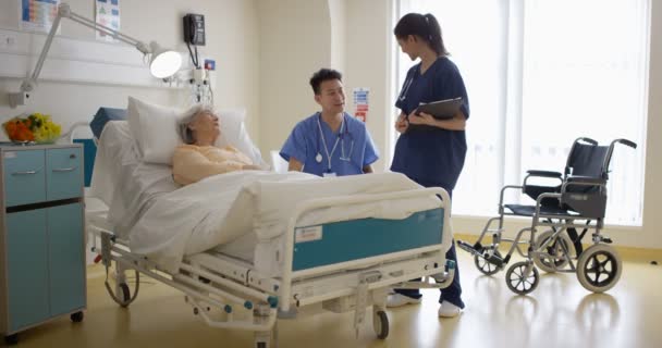 Caring Pracowników Medycznych Szpitalu Mówienie Starszej Pani Przy Jej Łóżku — Wideo stockowe