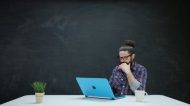 dizüstü bilgisayarda çalışan ve kara tahta ilham için bakarak 4 k Hipster adam