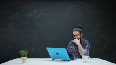 dizüstü bilgisayarda çalışan ve kara tahta ilham için bakarak 4 k Hipster adam