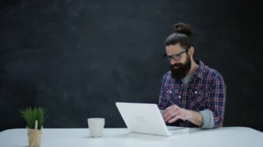 dizüstü bilgisayar kullanan ve boş kara tahta arka plan üzerinde düşünme 4 k Hipster adam