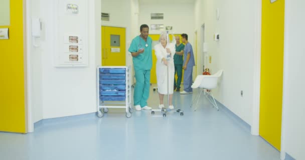 Заботливый Медицинский Работник Помогает Пожилой Пациентке Оживленной Больнице — стоковое видео