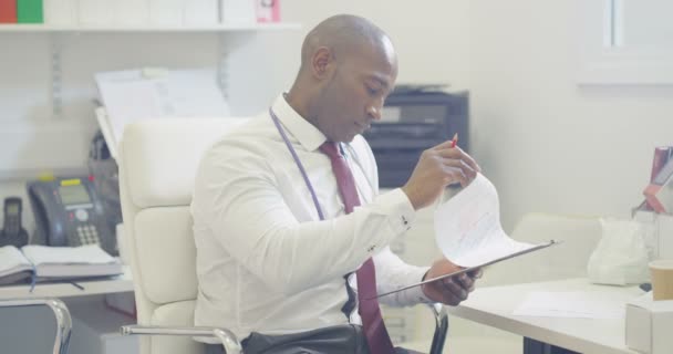 Γιατρός Κάθεται Μόνος Στο Γραφείο Γράφει Σημειώσεις Στον Ιατρικό Μητρώο — Αρχείο Βίντεο