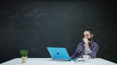 dizüstü bilgisayarda çalışan ve kara tahta ilham için bakarak 4 k Hipster adam