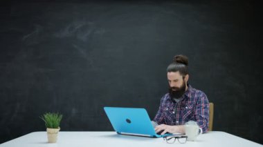 dizüstü bilgisayarda çalışan ve kara tahta ilham için bakarak 4 k Hipster adam